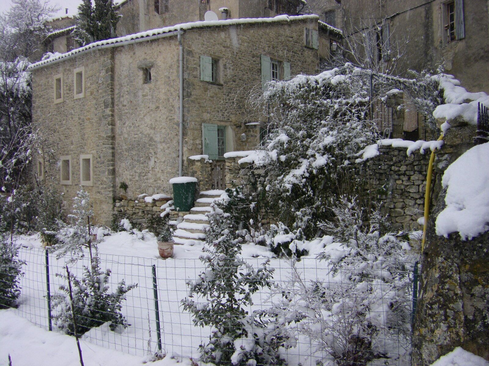 A stone building with multiple windows and a snow-covered roof.