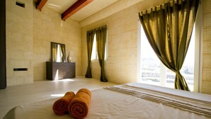 A hotel room with a large bed, a vanity with a mirror, and curtains on the windows. - Amazing views, complete privacy, luxury and comfort including pool and deck area (Ghasri)