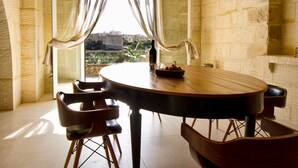 A dining area with a round table, four chairs, and a bowl of fruit. - Amazing views, complete privacy, luxury and comfort including pool and deck area (Ghasri)