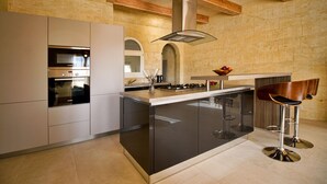 A modern kitchen with a central island, stainless steel appliances, and a bar area with stools. - Amazing views, complete privacy, luxury and comfort including pool and deck area (Ghasri)