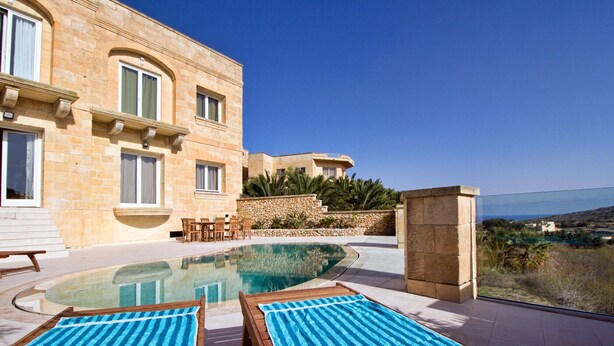 A pool area with lounge chairs and a stone building with arched windows. - Amazing views, complete privacy, luxury and comfort including pool and deck area (Ghasri)