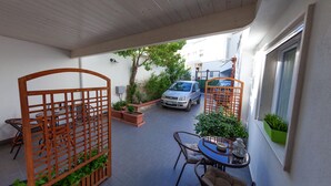 A covered patio area with a table and chairs, potted plants, and a parked car. - Cozy and comfortable apartment in Matera (Matera)