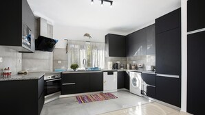 Una cocina moderna con gabinetes negros, horno empotrado, lavadora y cafetera.