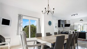Una cocina moderna con comedor, ventanas amplias y una l ámpara de araña.