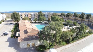 Ein Wohngebiet mit Schwimmbad, mehreren Gebäuden und freiem Blick auf das Meer.