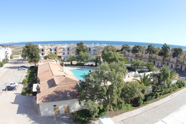 A residential area with a swimming pool, multiple buildings, and a clear view of the sea. - Sunny and modern apartment near the beach (Lagos, Portugal)