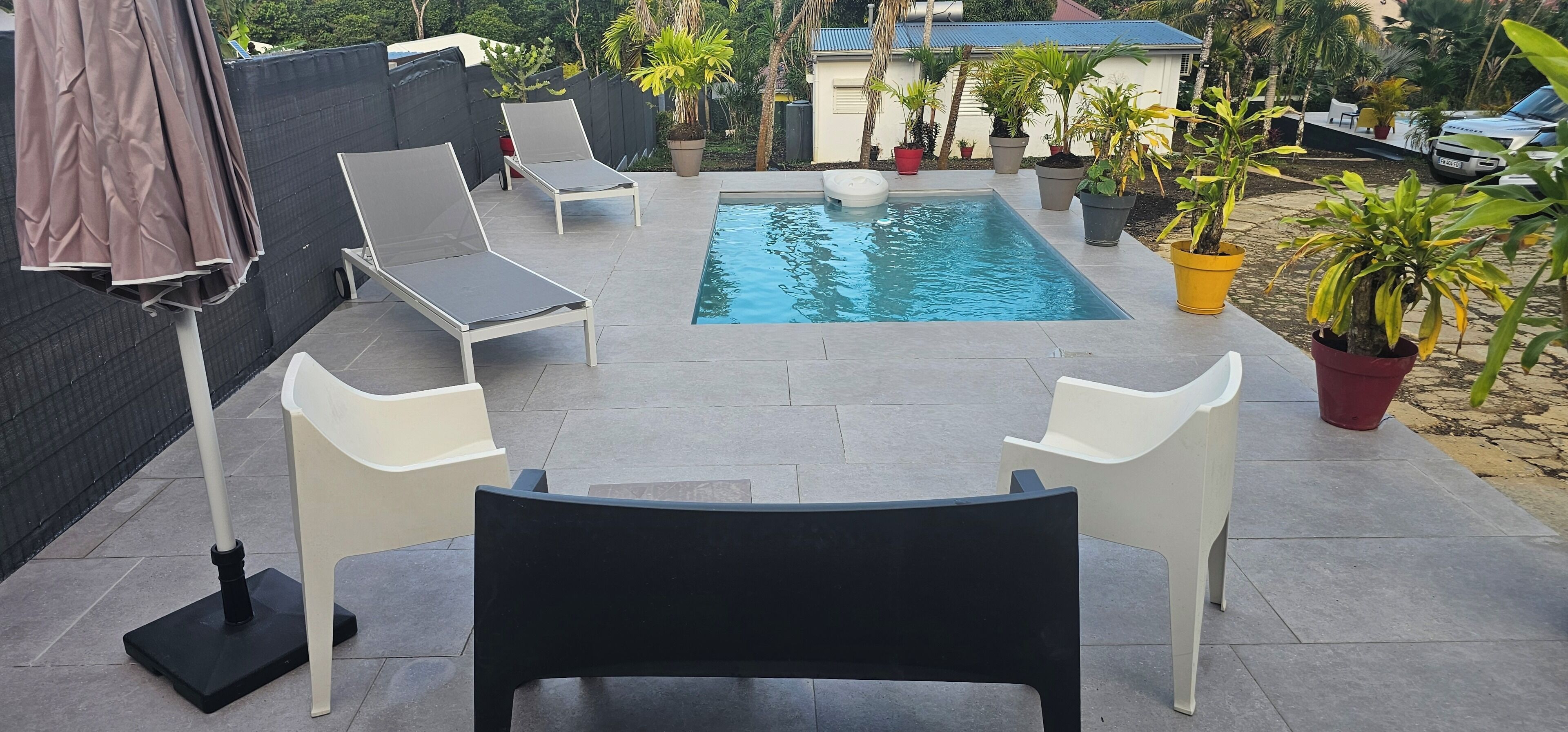 Ein Swimmingpool mit Liegestühlen und Kübelpflanzen.