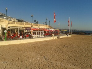 Een restaurant aan het strand met terras en vlaggen.
