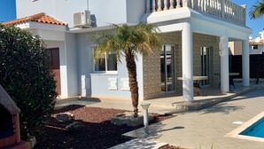 A two-story house with a balcony, a swimming pool, and a garden with a palm tree. - Private Villa With Large Private Pool Situated In Coral Bay, Paphos, Cyrprus (coral bay)