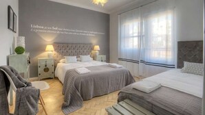 A modern bedroom with two beds, a grey and white color scheme, and a decorative wall quote.
