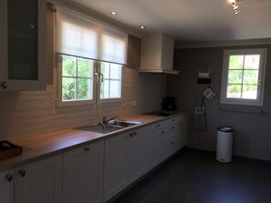 A modern kitchen with a large window, a built-in sink, and a coffee maker.