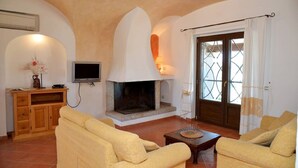 A living room with a fireplace, two sofas, a television, and a wooden cabinet. - Villa with private pool (arzachena)