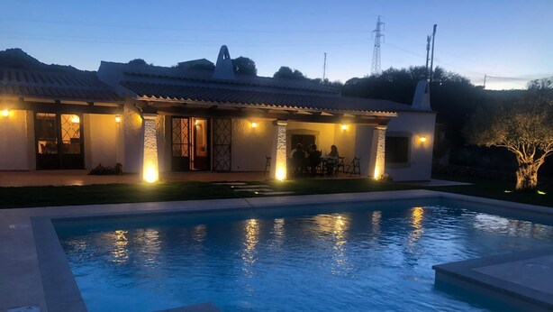 A swimming pool with a patio area and a building with outdoor lighting. - Villa with private pool (arzachena)