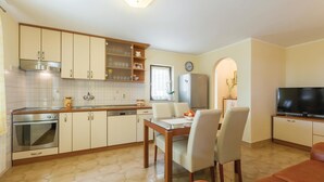 Una cocina compacta con comedor, refrigerador y televisor.