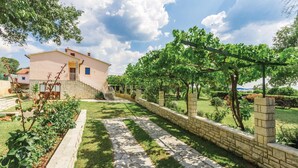 Una casa con un camino de piedra que lleva a una escalera, rodeada por un jardín cuidado y un viñedo.