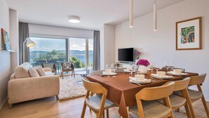 Una sala de estar moderna con comedor, ventanas amplias, televisor de pantalla plana y vistas al exterior.