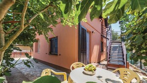 Un patio con una mesa y sillas, una escalera y un edificio con contraventanas.