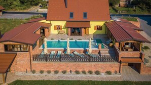Une maison à deux étages avec une piscine, un patio couvert et une façade en briques.