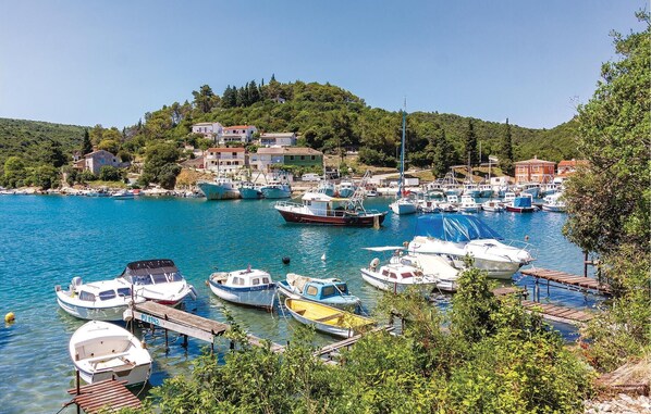 Enjoy a serene harbor scene with boats docked at the pier, surrounded by lush greenery and traditional buildings.