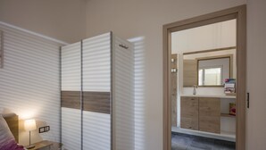 A bedroom with a bed, bedside table, lamp, wardrobe, and a mirror. - Welcome to the Millau holiday bungalow in the beautiful Zillertal (Schlitters)