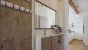 A modern bathroom with a wooden door, a large mirror, and a white vanity with a sink. - Welcome to the Millau holiday bungalow in the beautiful Zillertal (Schlitters)