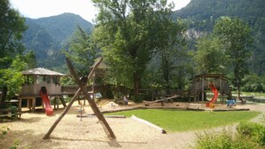 A playground with swings and slides, surrounded by trees and mountains. - Welcome to the Millau holiday bungalow in the beautiful Zillertal (Schlitters)