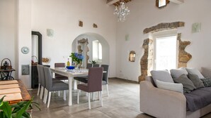 A dining area with a white table and chairs, a chandelier, and stone walls. - Pet friendly home in Ruzici (Ruzici)