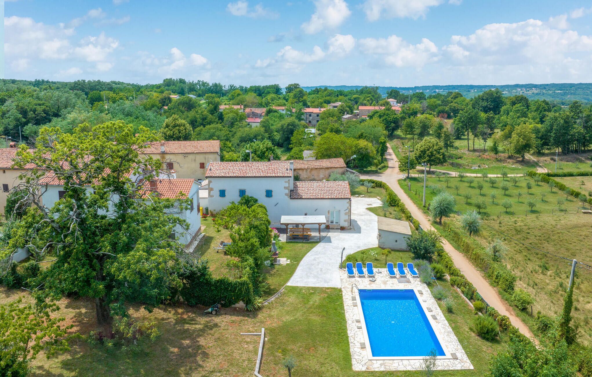 A villa with a swimming pool, surrounded by lush greenery and a clear view of the countryside.