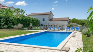 A rectangular swimming pool with a stone deck, surrounded by lounge chairs and a pergola. - Pet friendly home in Ruzici (Ruzici)