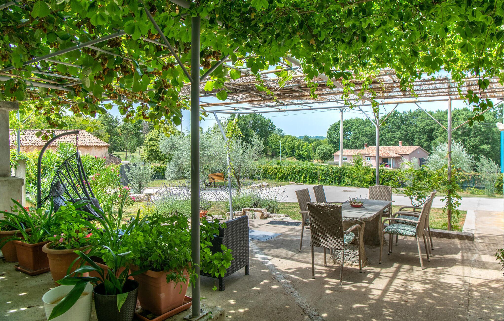 An outdoor patio with a pergola, wicker furniture, and potted plants.