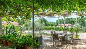 An outdoor patio with a pergola, wicker furniture, and potted plants. - Pet friendly home in Ruzici (Ruzici)