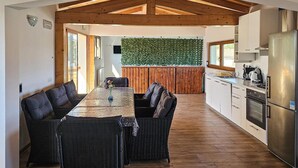 A modern kitchen with a stainless steel refrigerator, a built-in oven, and a wooden ceiling.