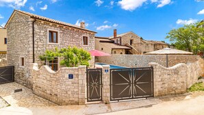 A stone building with a tiled roof, a gated entrance, and a small pool area.
