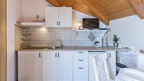 Een keuken met witte kastjes, een houten plafond en een betegelde spatwand.