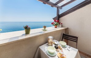 Un balcon avec une table dressée pour le dîner, donnant sur une étendue d’eau.