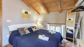 Een slaapkamer met een groot bed, een stenen muur, een houten plafond en een schilderij aan de muur.