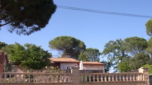 A residential area with a stone wall, a tiled roof house, and trees.