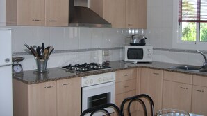 A kitchen with wooden cabinets, a gas stove, a microwave, and a sink.