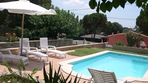 A swimming pool with white lounge chairs and an umbrella.
