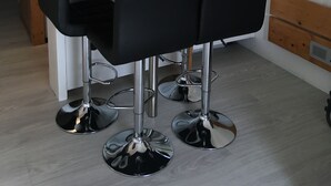 Una cocina moderna con armarios de madera, un lavamanos de acero inoxidable y una mesa grande con cuatro sillas negras.