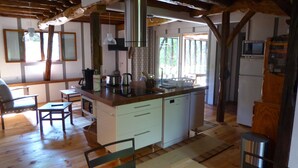 Una cocina con vigas de madera, una isla central y un comedor con sillas.