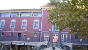 A building with a red facade, multiple windows, and a staircase with ornate railings. - Apartment in lake city of Grimaud harbor with beautiful view (Port Grimaud)