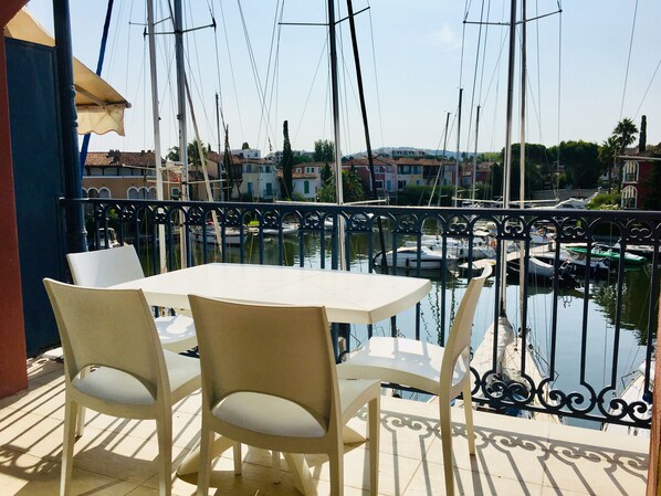 Ein Balkon mit Tisch und Stühlen mit Blick auf einen Jachthafen und Boote.