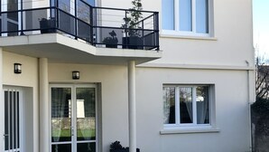 Een modern gebouw met twee verdiepingen, een balkon, een glazen deuropening en een klein raam.