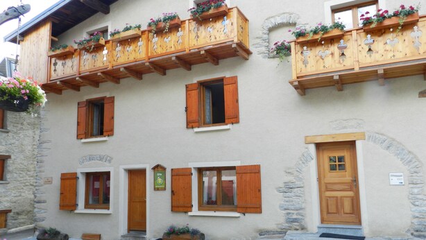 Un edificio tradicional con balcones de madera, paredes de piedra y una puerta central.