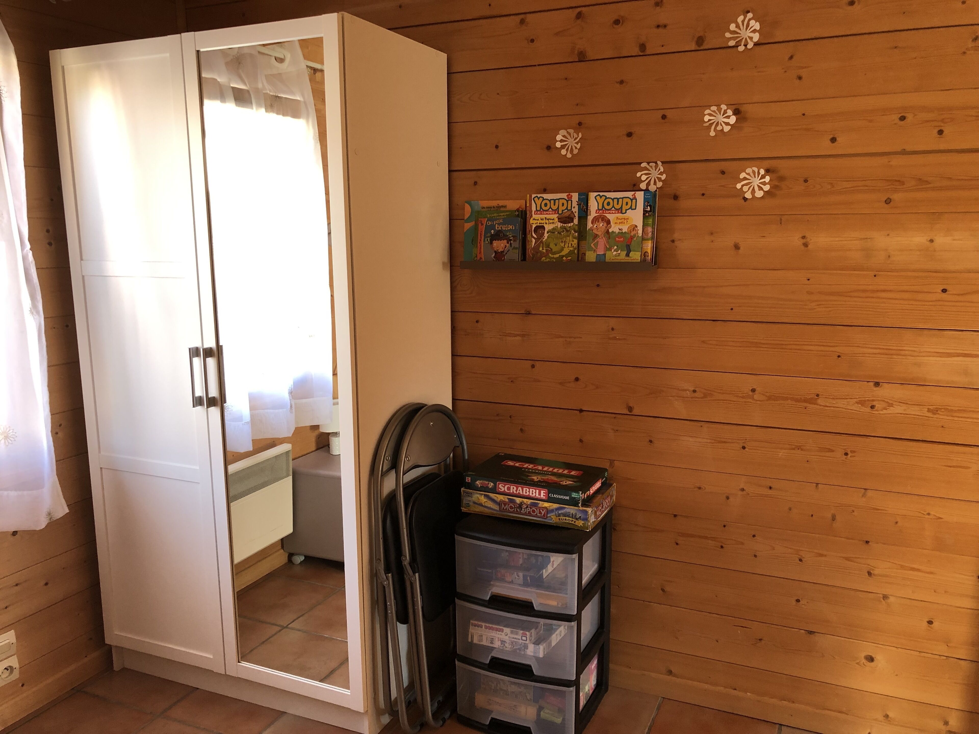 Una habitación con pared de madera, un armario y una estantería con juegos de mesa.