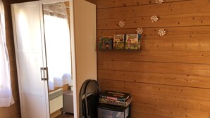 A room with a wooden wall, a wardrobe, and a shelf with board games. - Independent wooden chalet  (Le Tholy)