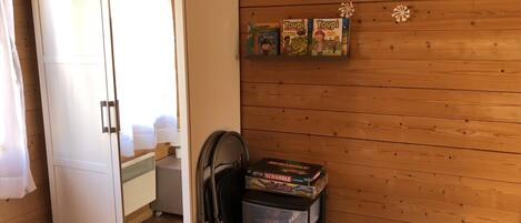 Una habitación con pared de madera, un armario y una estantería con juegos de mesa.