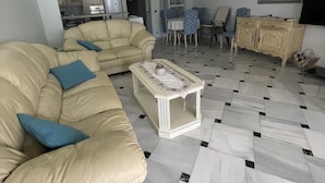 Una sala de estar con un sofá color beige, una mesa de centro y un comedor con mesa y sillas.