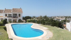Una piscina de borde curvo, rodeada por una terraza de piedra y un césped cuidado.